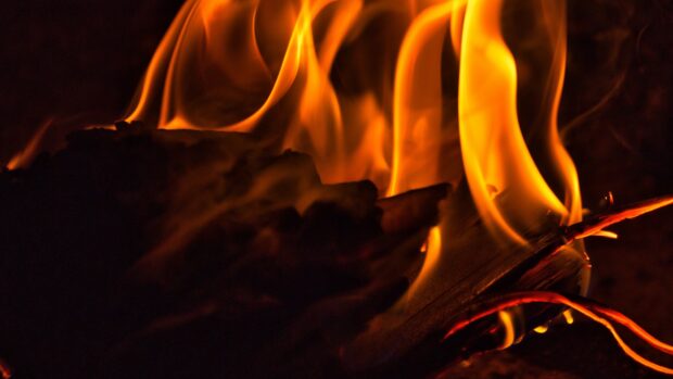A close up of a warm glowing fire with orange flames and burning wood, 4K Desktop Wallpaper