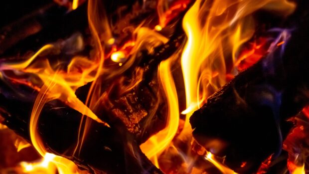 The fireplace flames glow warmly over the burning logs in this detailed view, 4K Desktop Wallpaper
