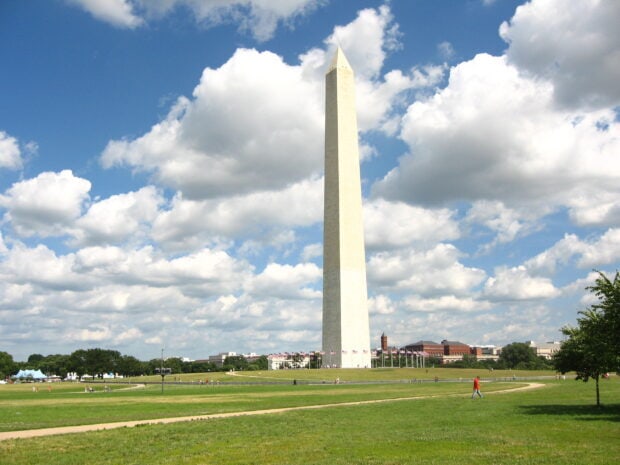 Washington Monument standing tall under a cloudy sky in a green park