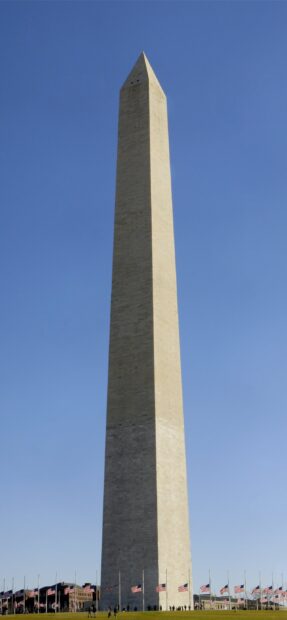 The Washington Monument is a tall stone obelisk located in Washington D.C against a clear blue sky