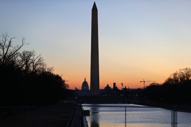 Washington Monument stands tall at sunset with reflections on the water in the cityscape