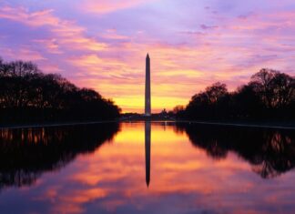 Washington Monument stands tall with vibrant sunset colors reflecting on the water