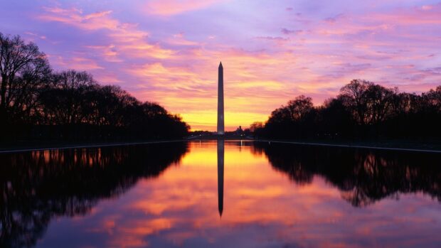 Washington Monument stands tall with vibrant sunset colors reflecting on the water