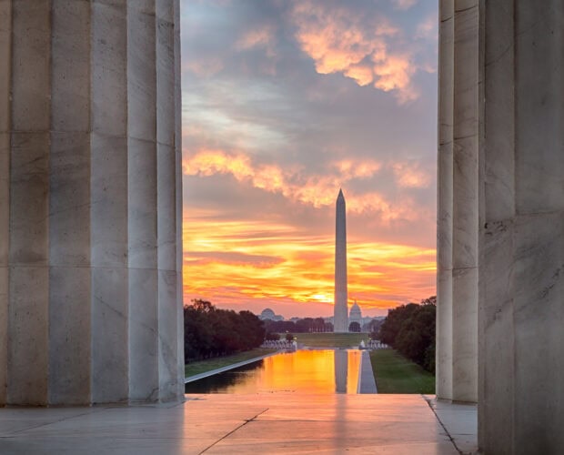 View of Washington Monument at sunrise from the Lincoln Memorial reflecting pool in Washington DC
