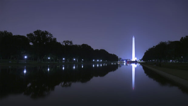 Washington Monument stands tall at night reflecting on the calm water surface