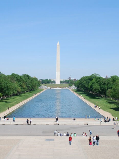 Washington Monument standing tall near the reflecting pool on a clear sunny day