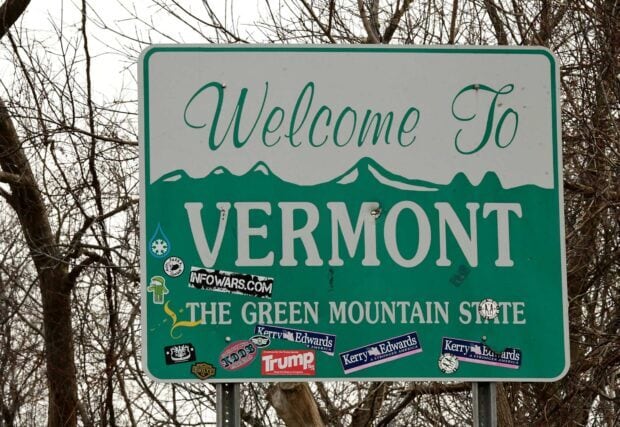 The Vermont signboard shows a welcome message with mountain graphics and various stickers, HD Desktop Wallpaper