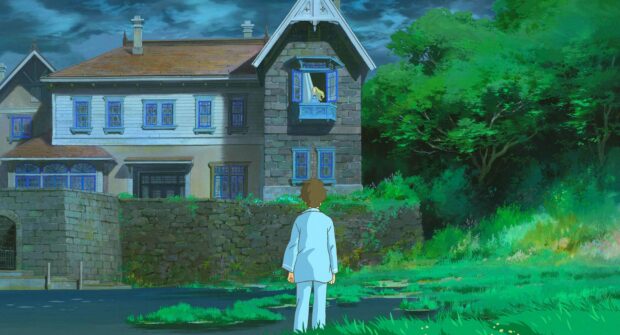 A boy in pajamas stands in front of a house while a girl looks out the window in When Marnie Was There anime