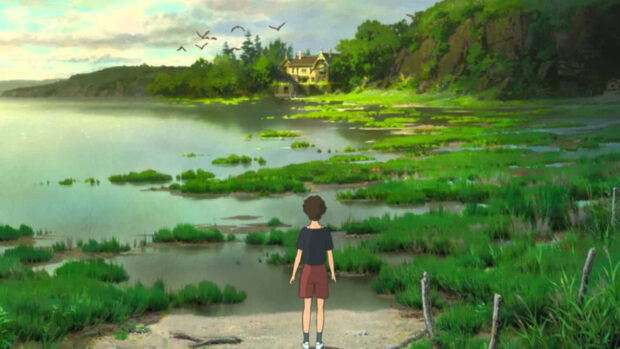 A boy standing by a green marsh near a calm lake in When Marnie Was There anime