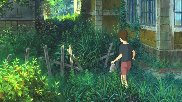 A boy from When Marnie Was There walking barefoot through lush green grass near an old building
