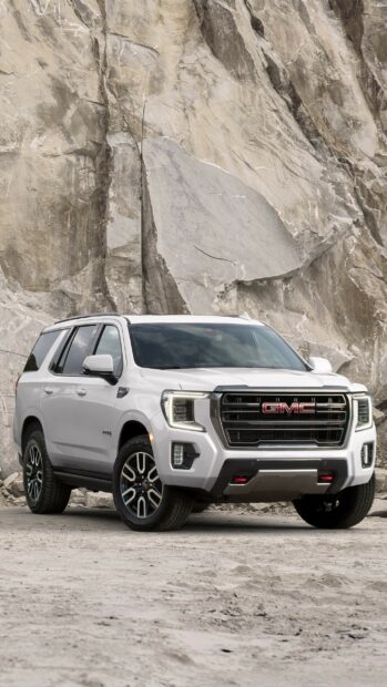 A white GMC SUV parked in front of a large rocky cliff under cloudy skies, 2K Mobile Wallpaper