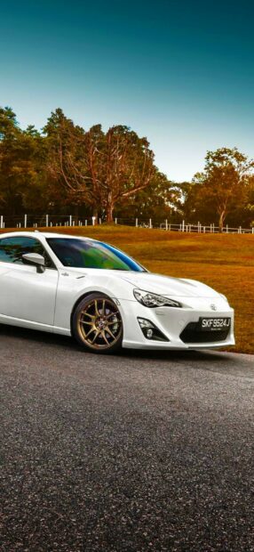 White toyota sports car in scenic outdoor setting with trees and open sky.