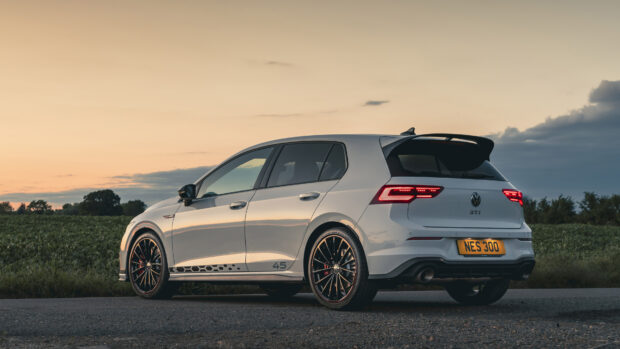 A white Volkswagen Golf GTI is parked on a road with a field and cloudy sky during sunset, 4K Desktop Wallpaper