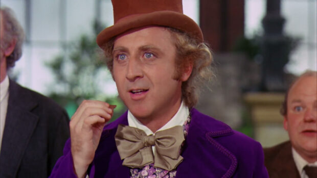 Willy Wonka character holding a chocolate piece in a purple coat and bow tie