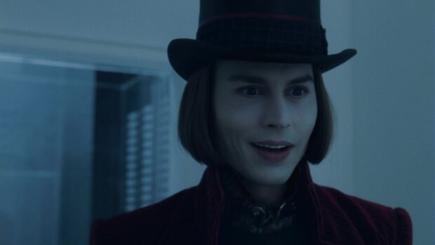 Willy Wonka character smiling in dark attire wearing a hat indoors