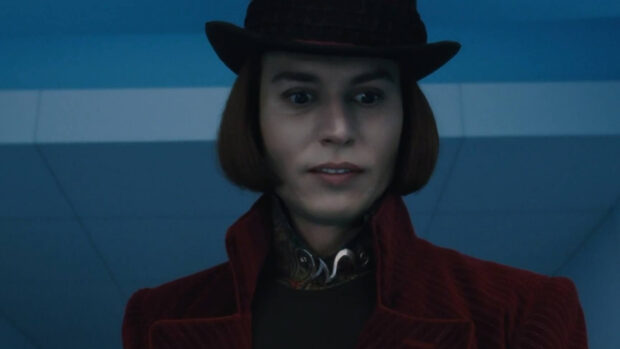 Willy Wonka character wearing a dark red coat and hat looking surprised indoors