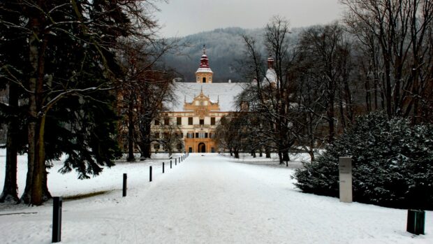 A snow covered path leads to a historic building surrounded by leafless trees in Austria, HD Desktop Wallpaper