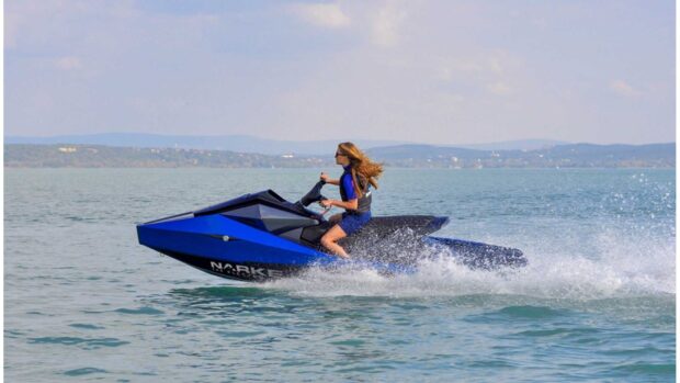 A woman is riding a blue jet ski across a calm lake with hills in the background, HD Desktop Wallpaper