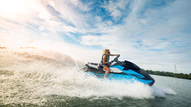 A woman enjoys riding a blue jet ski swiftly across the water under a clear sky, HD Desktop Wallpaper