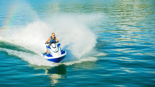 A woman is enjoying riding a jet ski with water splashing around her on a sunny day, HD Desktop Wallpaper