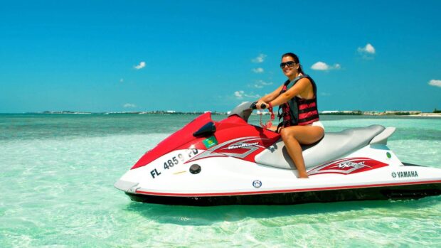 A woman enjoys riding a red and white jet ski on clear ocean water under a bright blue sky, HD Desktop Wallpaper