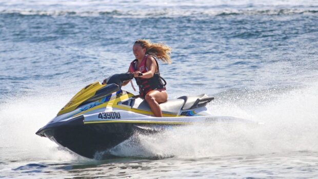 A woman is enjoying riding a yellow jet ski creating splashes on the water surface, HD Desktop Wallpaper