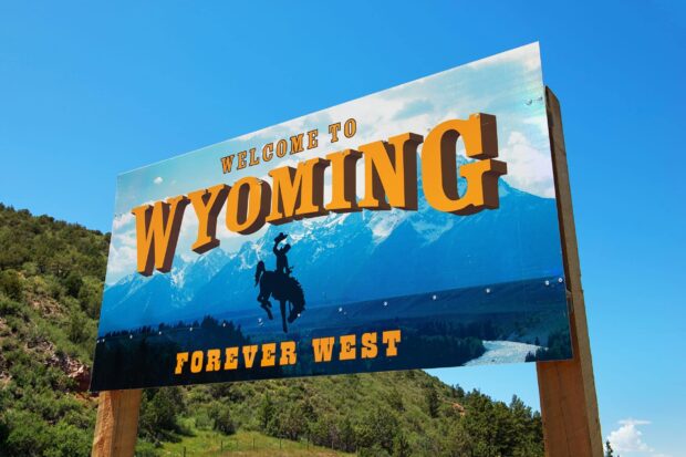 Welcome to Wyoming sign with a cowboy silhouette in a mountainous landscape