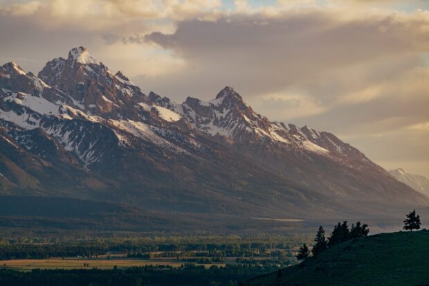 Snow capped Wyoming mountain range with forested valley below at sunset