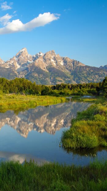 Wyoming landscape with snow capped mountains reflected in a calm river