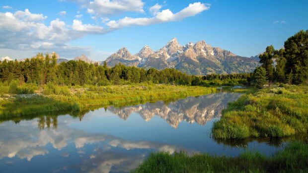 A beautiful Wyoming landscape with mountains and river reflecting clear blue sky and greenery