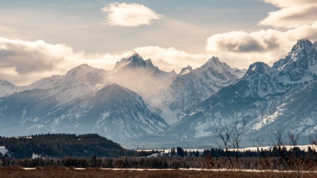 Snow covered mountain range in Wyoming with misty clouds above the peaks