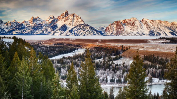 Snowy mountain range and evergreen forest landscape in Wyoming at sunset