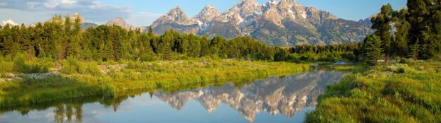 Wyoming natural landscape with mountains and river reflecting clear sky and greenery