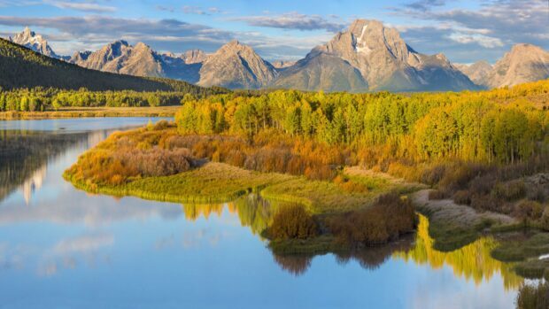 Autumn colors of Wyoming mountains and forests reflected in calm river water at sunrise