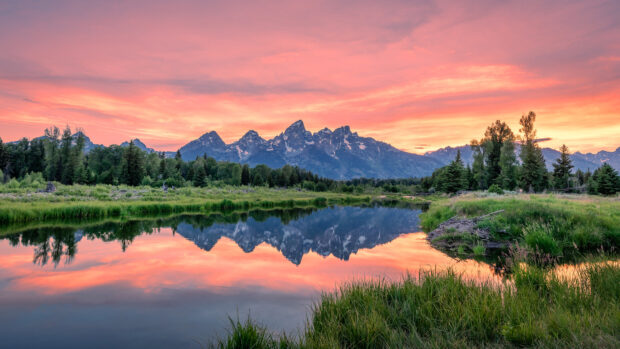Mountain range in Wyoming reflecting on calm river at sunset in Wyoming