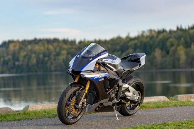 A Yamaha superbike parked on a lakeside road with forest background