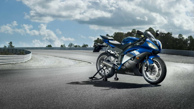 Blue Yamaha sport motorcycle parked on racetrack under cloudy sky