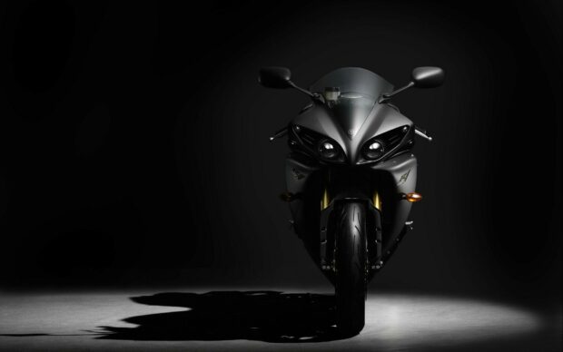 Front view of Yamaha motorcycle in dark studio lighting with sharp shadows