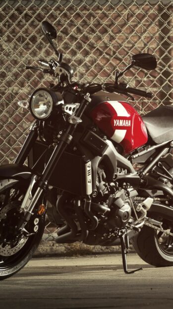 Close up of a Yamaha motorcycle parked in front of a chain link fence