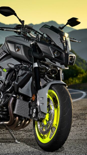 Close up of Yamaha motorcycle front wheel and headlight against mountain background