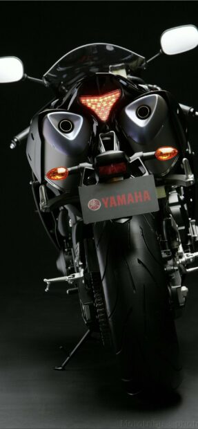 Rear view of a Yamaha motorcycle with glowing tail light and rear tire