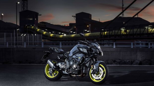 A Yamaha motorcycle with neon yellow wheels parked on an urban street at dusk