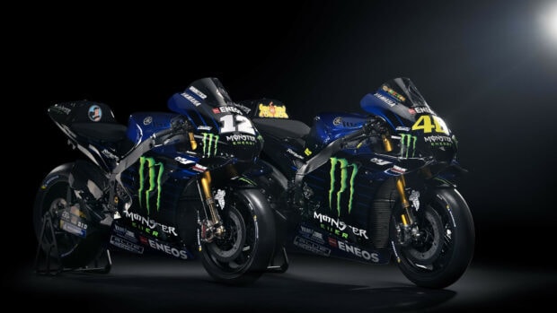 Two Yamaha racing motorcycles with Monster Energy logos in a dark studio setting