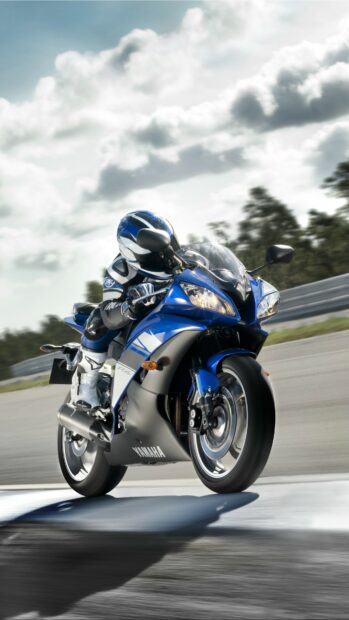 A rider wearing blue gear riding a Yamaha sport motorcycle at high speed on a race track