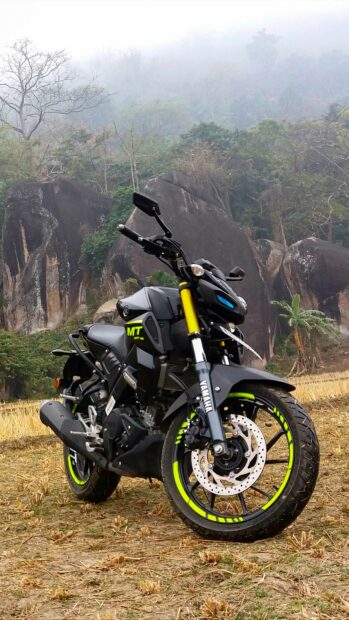 Yamaha motorcycle MT model parked on a dry field with rocky hills and foggy forest background