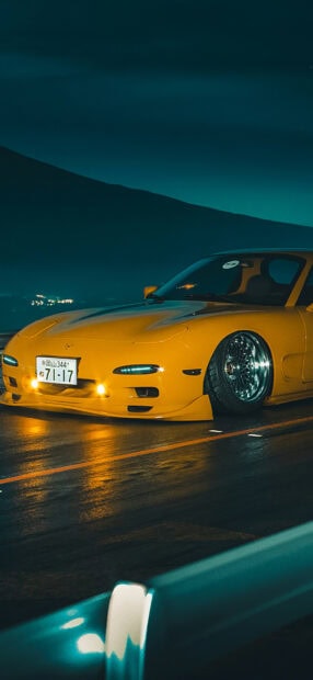 A yellow Mazda sports car is parked on a wet road under the night sky with mountains in the background, HD Phone Wallpaper