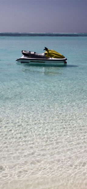 A yellow jet ski floats calmly on the clear turquoise water in a serene ocean setting, 2K Phone Wallpaper