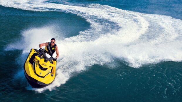 A man rides a yellow jet ski creating waves on the ocean, HD Desktop Wallpaper
