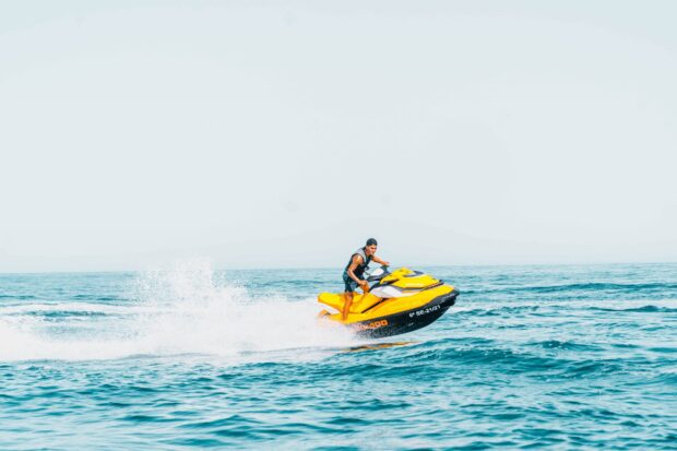 A man riding a yellow jet ski across the blue ocean water, 2K Desktop Wallpaper