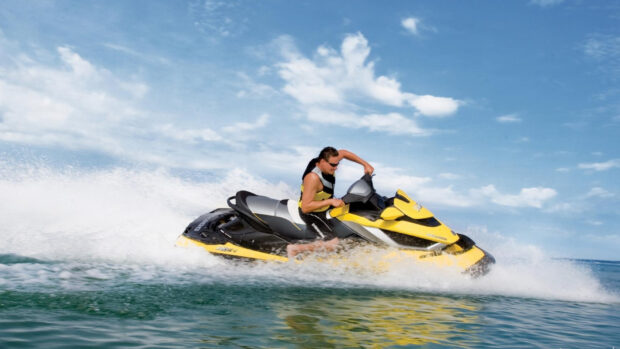 A man rides a yellow jet ski swiftly across the ocean under a partly cloudy sky, HD Desktop Wallpaper